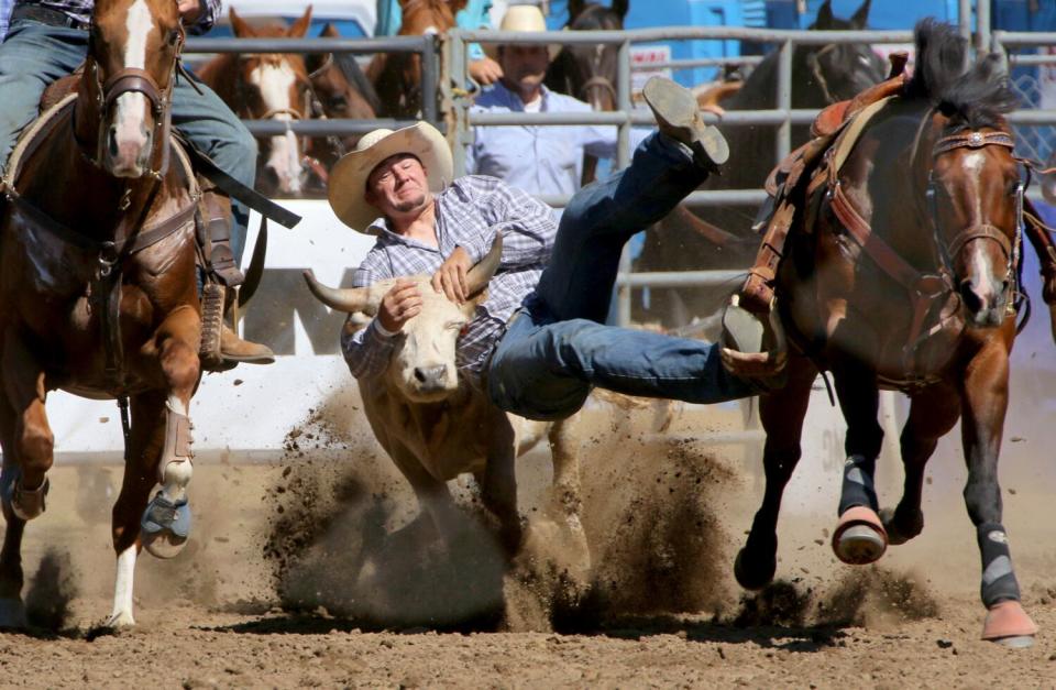 A man hangs on to the head of a running bull.