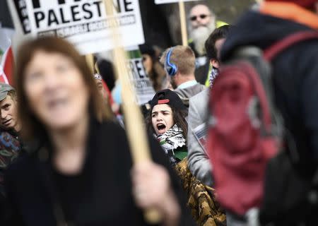 A demonstrator holds a placard as others shout slogans as they protest against Israel's Prime Minister Benjamin Netanyahu's visit, opposite Downing Street in London, Britain, Fberuary 6, 2017. REUTERS/Dylan Martinez