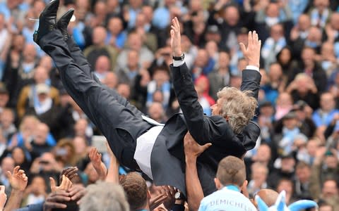 Manuel Pellegrini is thrown in the air by the Man City players - Credit: AFP