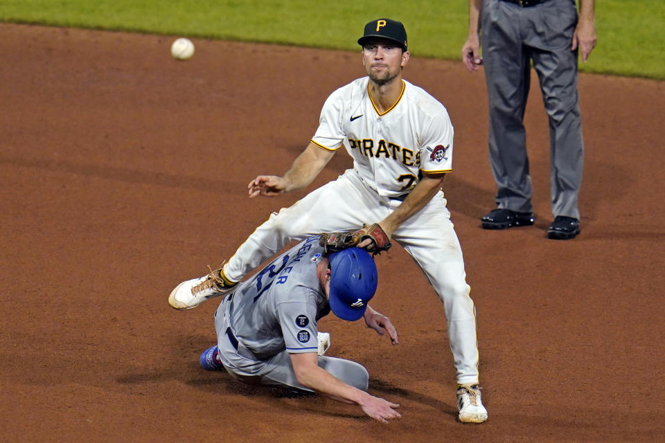 Pittsburgh Pirates second baseman Adam Frazier, top, makes the throw to first as he steps over Los Angeles Dodgers' Walker Buehler, after getting the force at second, to complete a double play on Mookie Betts during the seventh inning of a baseball game in Pittsburgh, Tuesday, June 8, 2021. (AP Photo/Gene J. Puskar)