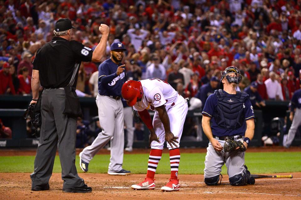 St. Louis Cardinals pinch-runner Adolis Garcia reacts as he is called out by umpire Ted Barrett tripping rounding third and being tagged out at home by Milwaukee Brewers catcher Erik Kratz.