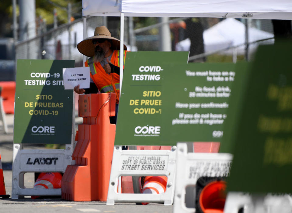 A worker holds up a sign asking for registration before entering a drive-thru COVID-19 testing facility at Dodger Stadium on May 28, 2020 in Los Angeles, California. | Harry How — Getty Images