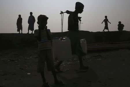 Internally displaced Rohingyas are silhouetted along the river bank where their fishing boats are docked, in Thae Chaung IDP camp on the outskirts of Sittwe, February 15, 2015. REUTERS/Minzayar