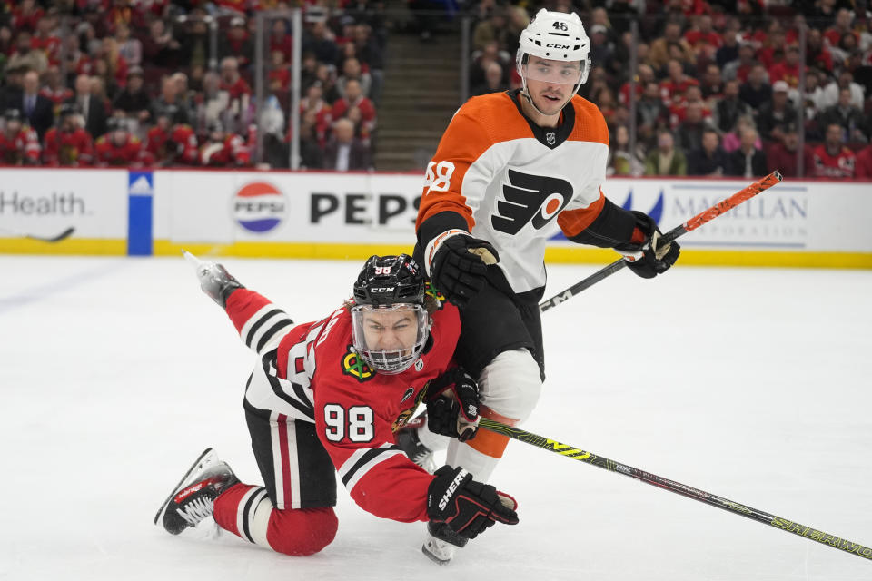 Chicago Blackhawks center Connor Bedard, left, trips over Philadelphia Flyers center Morgan Frost during the second period of an NHL hockey game Wednesday, Feb. 21, 2024, in Chicago. (AP Photo/Erin Hooley)