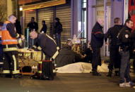 A general view of the scene that shows rescue services personnel working near the covered bodies outside a restaurant following a shooting incident in Paris, France, November 13, 2015. REUTERS/Philippe Wojazer