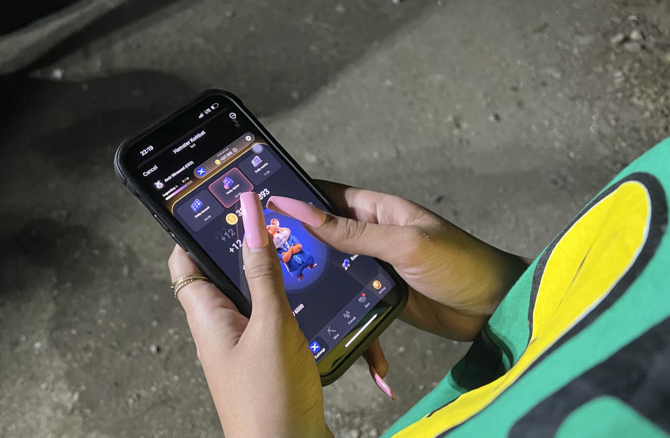 A woman plays Hamster Combat game on a cell phone in Tehran, Iran, Sunday, June 23, 2024. The rise of the “Hamster Kombat” app in Iran highlights a harsher truth facing the Islamic Republic's economy ahead of its presidential election this week to replace the late President Ebrahim Raisi, who died in a helicopter crash in May. (AP Photo/Vahid Salemi)