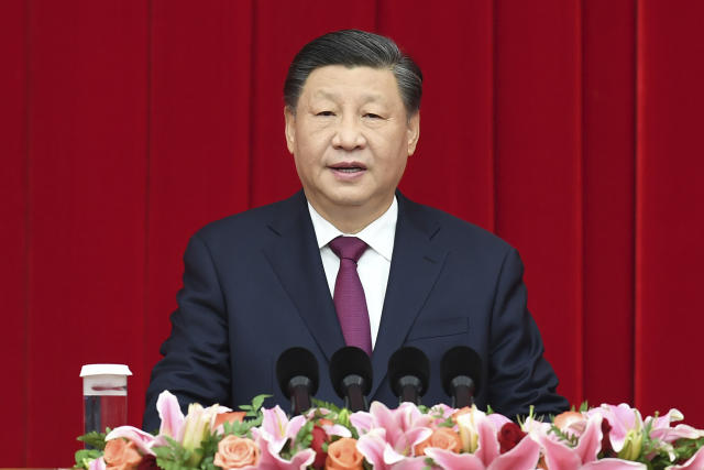 Xi Jinping makes an address in front of a red curtain.
