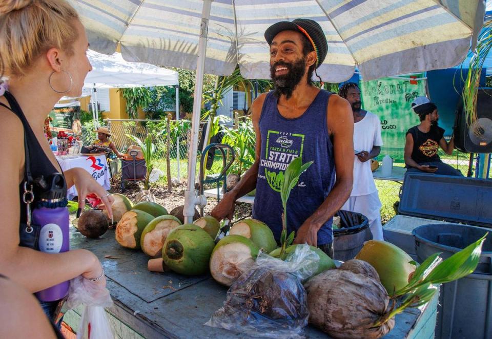 Kerwin Rowlins sells a fresh coconut to a patron at his booth at the Coconut Grove Saturday Organic Farmers Market, on Saturday, August 12, 2023.