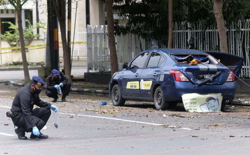 Police officers collect evidence from around the site of a bomb attack at the Sacred Heart of Jesus Cathedral in Makassar, South Sulawesi, Indonesia, Monday, March 29, 2021. Two attackers believed to be members of a militant network that pledged allegiance to the Islamic State group blew themselves up outside the packed Roman Catholic cathedral during a Palm Sunday Mass on Indonesia's Sulawesi island, wounding a number of people, police said. (AP Photo/Masyudi S. Firmansyah)