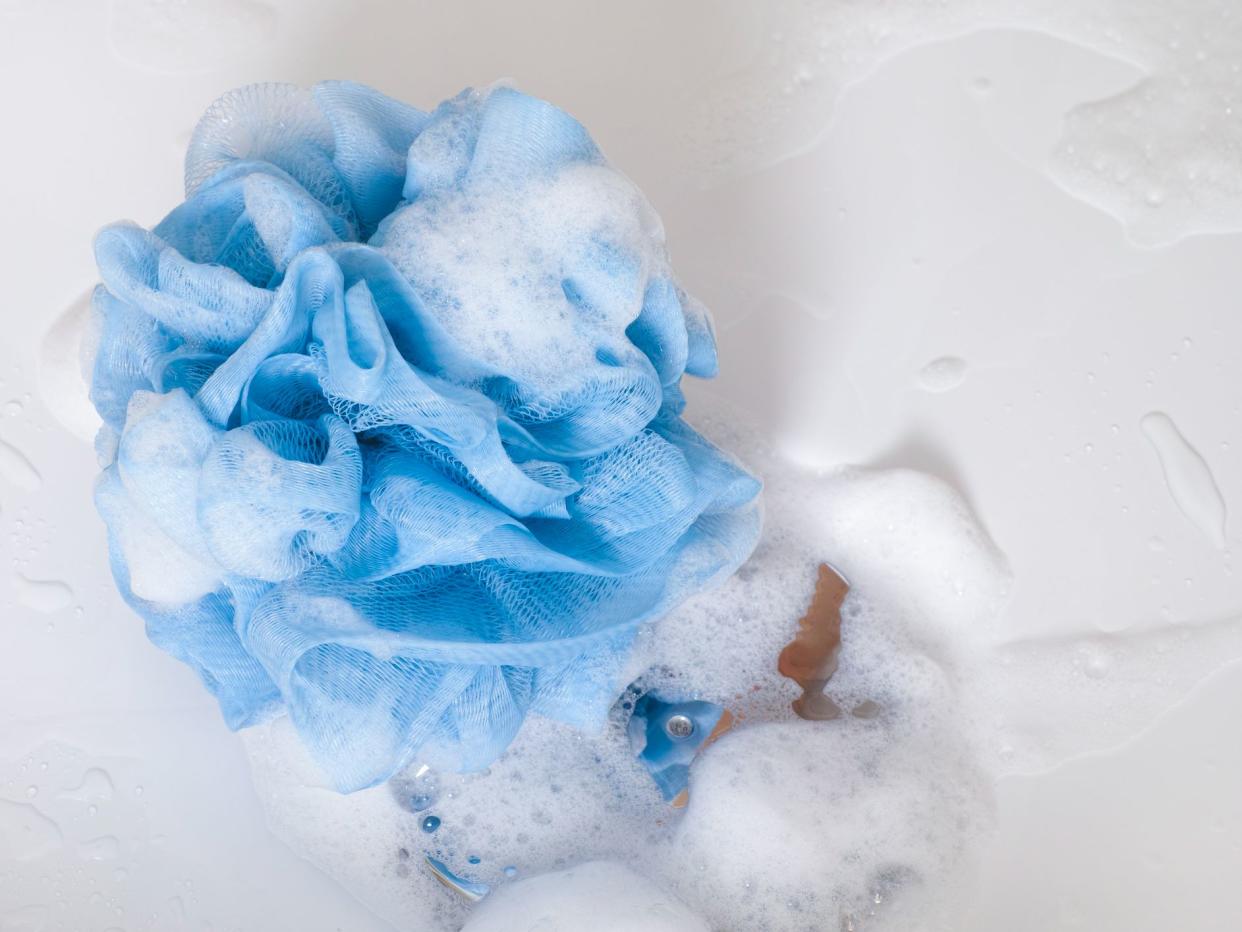 Blue sponge with foam on shower bath floor. Close-up.