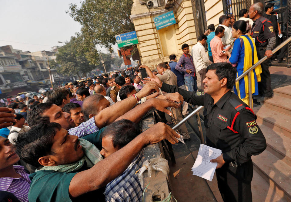 A security guard hands out request slips for the exchange of old high denomination bank notes