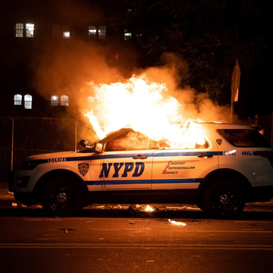 An NYPD police car is set on fire as protesters clash with police during a march against the death in Minneapolis police custody of George Floyd - Reuters