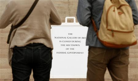 A couple from Japan reads a sign informing them of the closure of the National Gallery of Art in Washington October 1, 2013. REUTERS/Kevin Lamarque