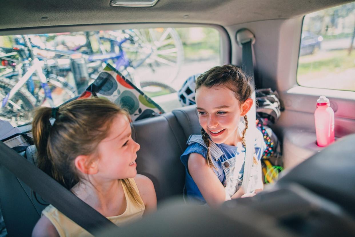 An image of two sisters sitting in a car on a road trip.