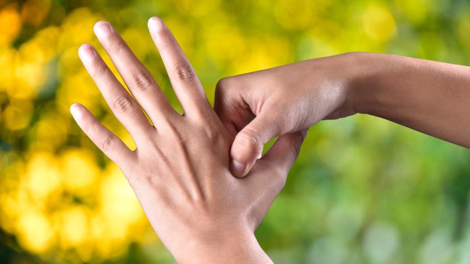 A woman pressing an acupressure spot on her hand as a migraine self-care remedy