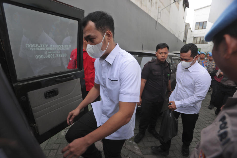 Police officers Bambang Sidik Achmadi, left, and Wahyu Setyo Pranoto are escorted by security guards to a prosecutors' van after their sentencing hearing at a district court in Surabaya, Indonesia, Thursday, March 16, 2023. The Indonesian court on Thursday acquitted Achmadi and Pranoto who were charged with negligence leading to the deaths of 135 people in October when police fired tear gas inside a stadium during a soccer match, setting off a panicked run for the exits. Another officer Has Darmawan was sentenced to 18 months in prison in the case that has sparked public outrage. (AP Photo/Trisnadi)