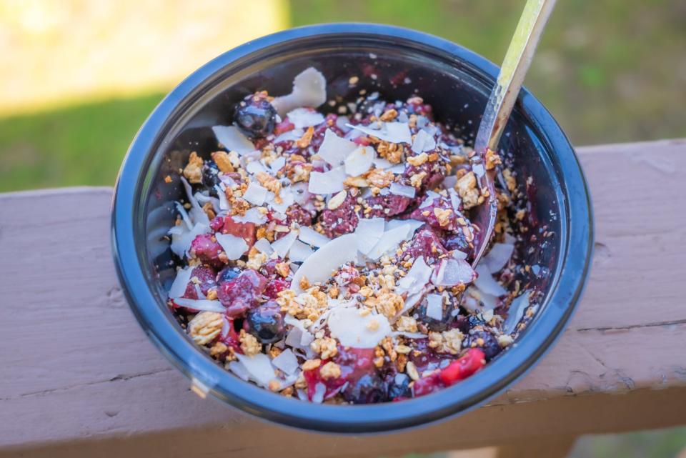 acai bowl with coconut shreds on top on the edge of a railing