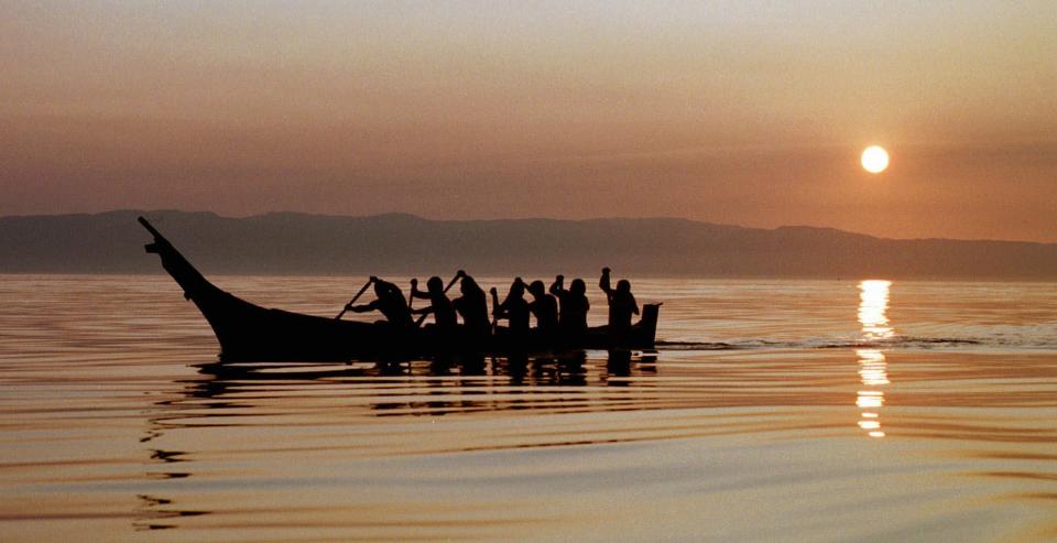 FILE - In this Aug. 20, 1998, file photo, Makah Indians paddle away from the rising sun as they head from Neah Bay, Wash., toward open Pacific Ocean waters during a practice for a planned whale hunt. Two decades after the Makah Indian tribe in the northwestern corner of Washington state conducted its last legal whale hunt from a hand-carved canoe, lawyers, government officials and animal rights activists will gather in a small hearing room in Seattle to determine whether the tribe will be allowed once again to harpoon gray whales as its people had done from time immemorial. (AP Photo/Elaine Thompson, File)