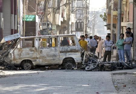 People stand behind damaged motorcycles and a van that were set alight by protesters during a demonstration by members of the Jat community in Rohtak, in the northern state of Haryana, India, February 21, 2016. REUTERS/Stringer