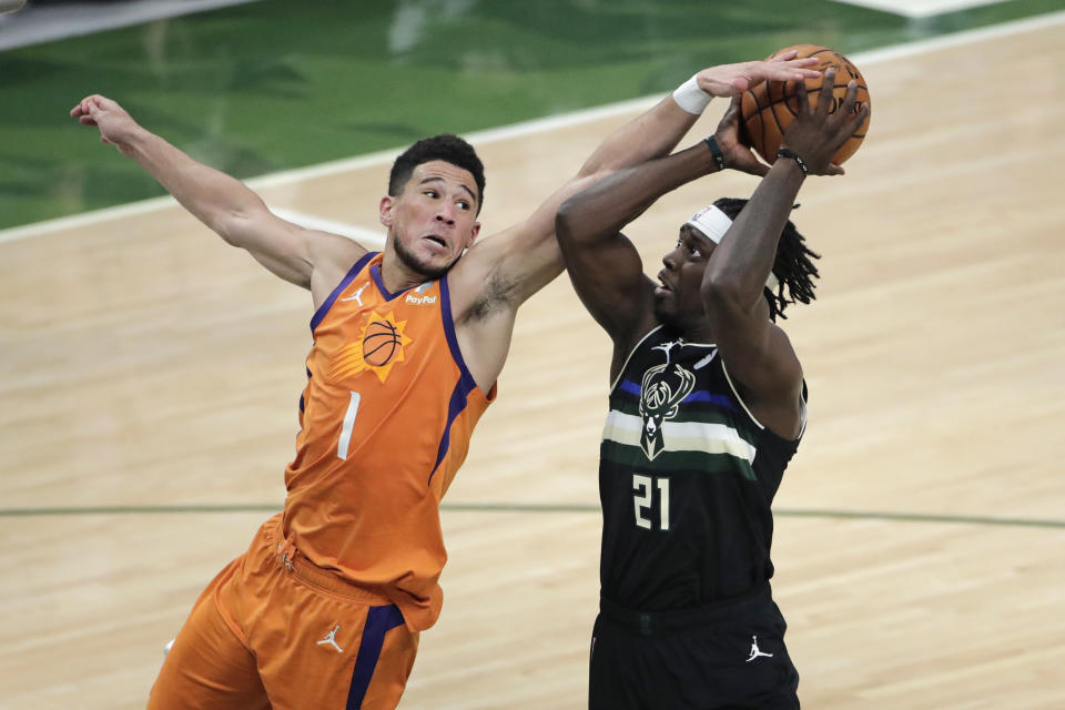 Milwaukee Bucks guard Jrue Holiday (21) is fouled by Phoenix Suns guard Devin Booker (1) during the second half of Game 6 of basketball's NBA Finals Tuesday, July 20, 2021, in Milwaukee. (AP Photo/Aaron Gash)