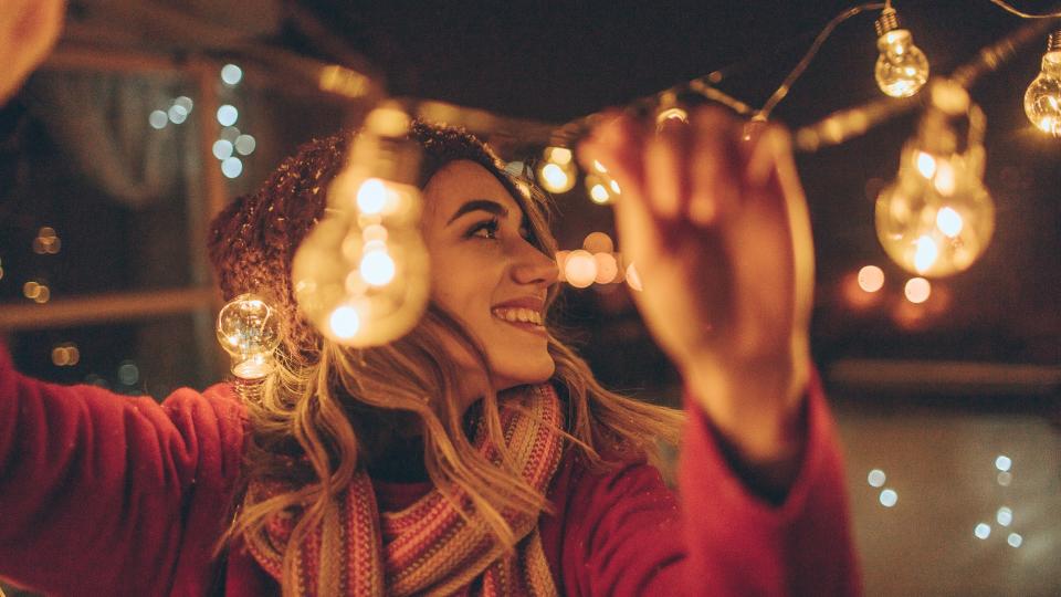 Photo of a young woman who is hosting New Year's party and having the last preparations on the venue - charming balcony over the city.