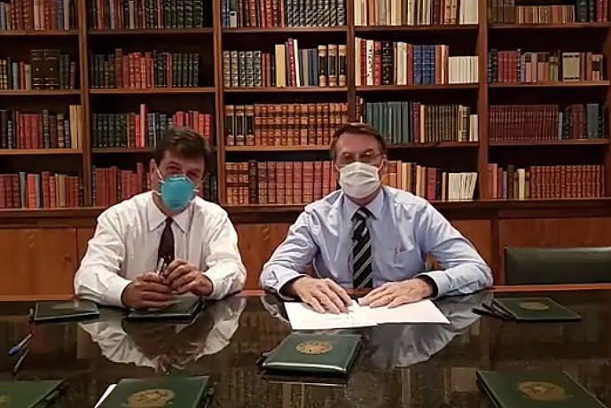 In this handout photo released by Brazil's Presidential Press Office, Brazilian Health Minister Luiz Henrique Mandetta, left, and President Jair Bolsonaro, wear masks as they speak about the new coronavirus during a Facebook Live transmission, in Brasilia, Brazil, Thursday, March 12, 2020. Bolsonaro has tested negative for the new coronavirus, according to a post Friday on his official Facebook profile. Bolsonaro, 64, received the test on Thursday after his communications director was confirmed to have the virus.(Brazil's Presidential Press Office via AP)