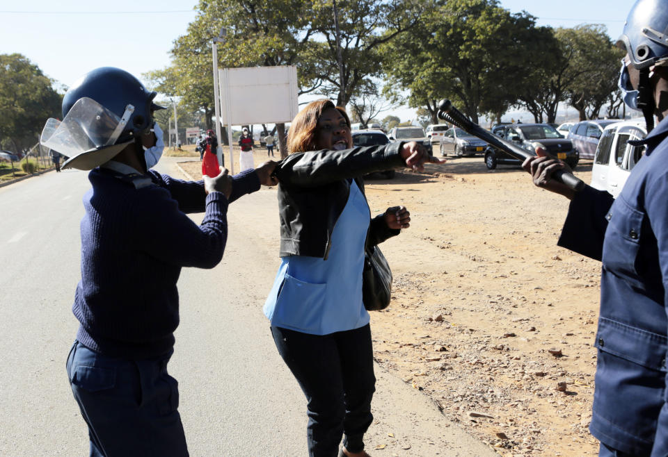 Riot police arrest a nurse who was protesting at a government hospital in Harare, Monday, July, 6, 2020. Thousands of nurses working in public hospitals stopped reporting for work in mid-June, part of frequent work stoppages by health workers who earn less than $50 a month and allege they are forced to work without adequate protective equipment. On Monday, dozens of nurses wearing masks and their white and blue uniforms gathered for protests at some of the country’s biggest hospitals in the capital, Harare, and the second-largest city of Bulawayo.(AP Photo/Tsvangirayi Mukwazhi)