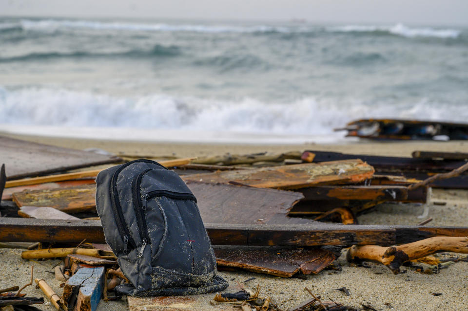 FILE - This Feb. 27, 2023 file photo shows a backpack sitting among the wrecked timbers of a migrant boat that capsized in the early morning of Sunday, Feb. 26, 2023, at a short distance from the shore in Steccato di Cutro, in the Italian southern tip, killing at least 94 people. Survivors and family members of the victims are converging in the area for a commemoration on Monday, Feb. 26, 2024, on the first anniversary of the disaster. (AP Photo/Valeria Ferraro)