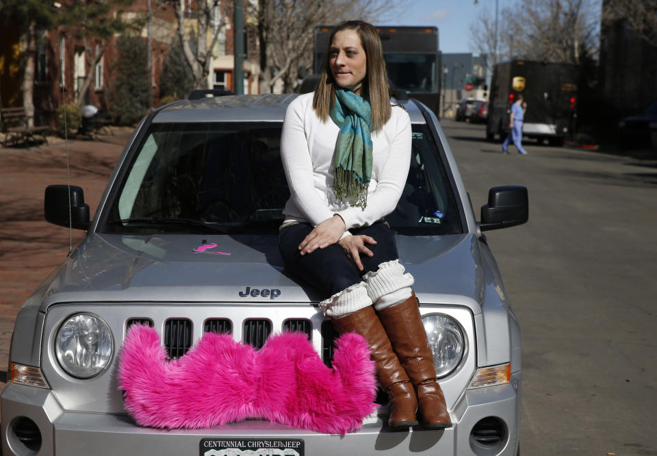 In this Feb. 28, 2014 photo, part time Lyft driver Brittany Cameron sits on the hood of her own vehicle, which she uses to give rides, and which is adorned with Lyft's trademark pink mustache, in downtown Denver. Lyft is a transportation network company whose mobile-phone application facilitates peer-to-peer ridesharing by enabling passengers who need a ride to request one from drivers who have a car. A dramatic change in the way people hail rides is shaking up decades of regulation now that getting a lift is as easy as making a few taps on a phone. (AP Photo/Brennan Linsley)