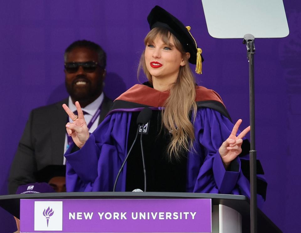 Taylor stands on stage in a cap and gown