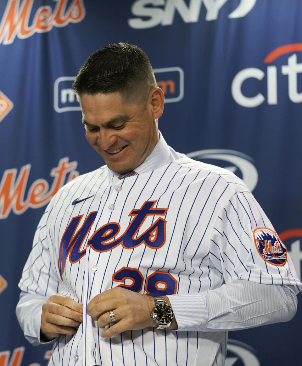 New York Mets baseball team new manager Carlos Mendoza buttons up a team jersey after his introduction at a press conference, Tuesday, Nov. 14, 2023, at Citifield in New York. (AP Photo/Bebeto Matthews)