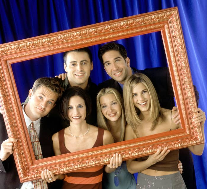 The cast of Friends holding up a picture frame to frame themselves inside it