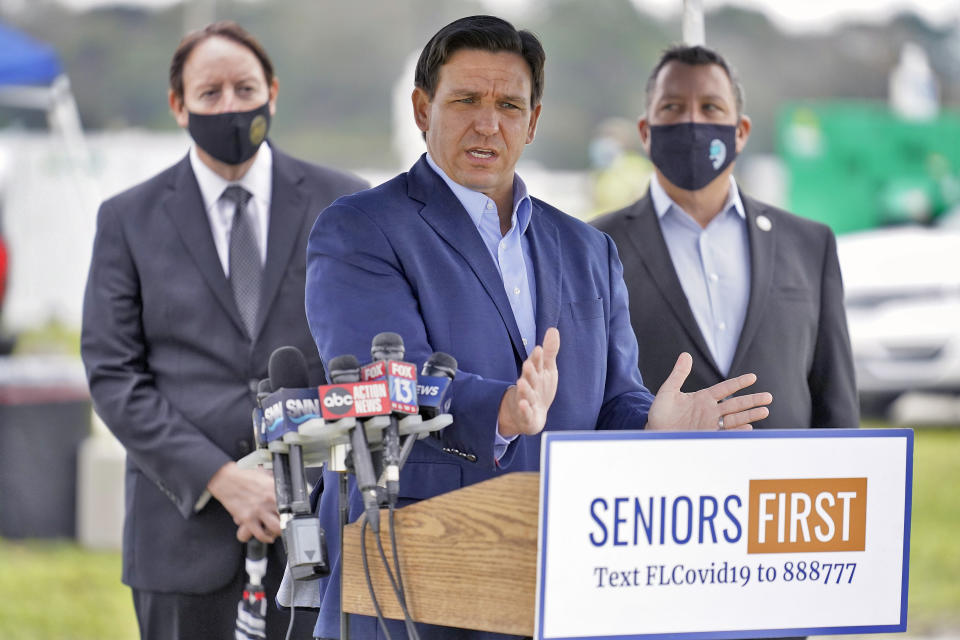 DeSantis stands at a podium with microphones and a plaque reading: Seniors first, text FLCovid19 to 888777.