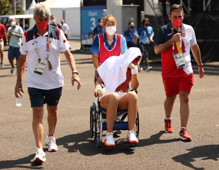 Paula Badosa of Spain is helped from the court in a wheelchair after retiring from her women's singles quarterfinal July 28.