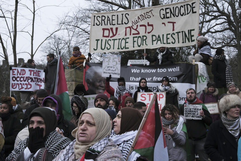 Protestors hold signs and wave Palestinian flags during a demonstration march outside the International Court of Justice in The Hague, Netherlands, Thursday, Jan. 11, 2024. The United Nations' top court opens hearings Thursday into South Africa's allegation that Israel's war with Hamas amounts to genocide against Palestinians, a claim that Israel strongly denies. (AP Photo/Patrick Post)