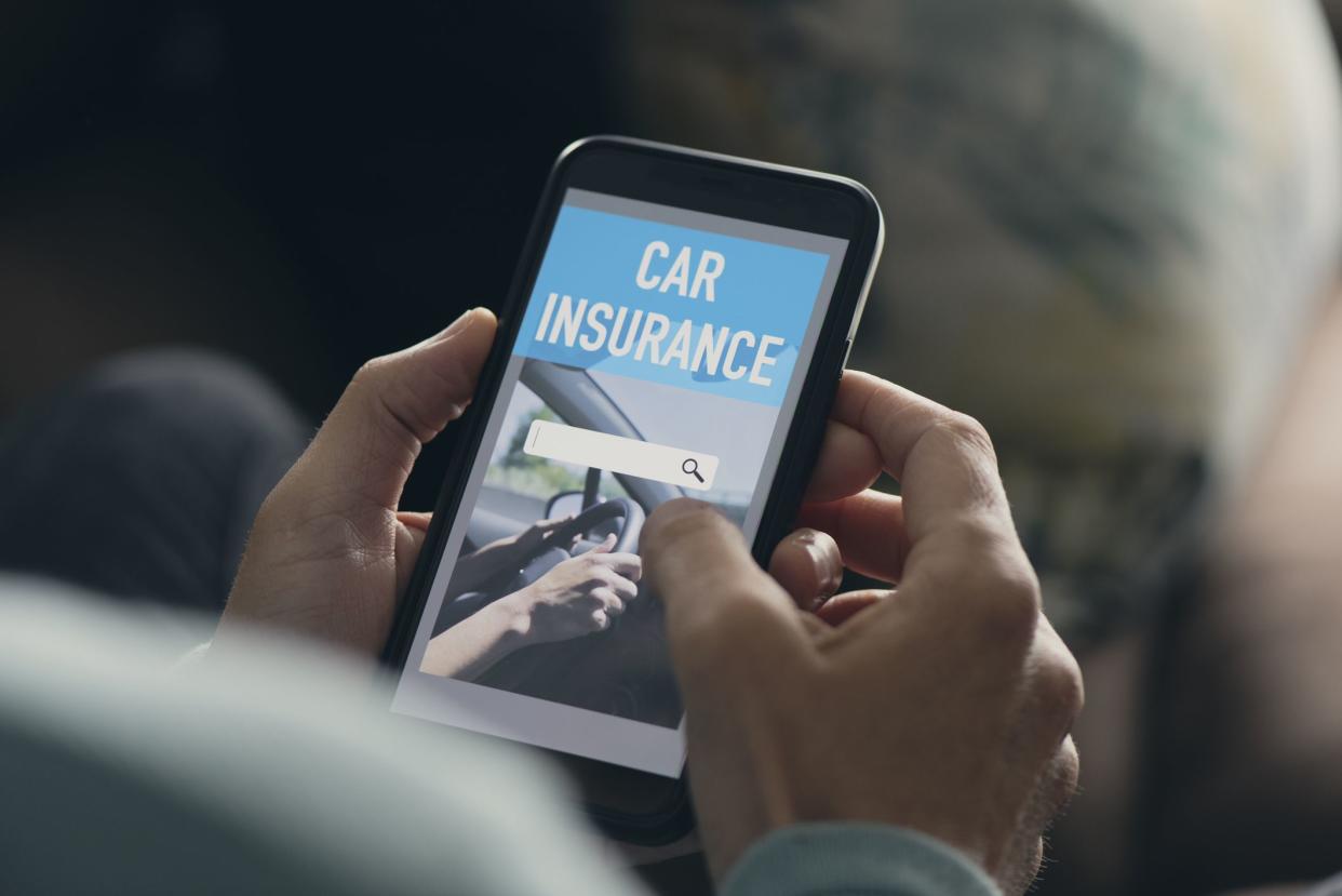 closeup of a young caucasian man, sitting at his living room, searching a car insurance online on his smartphone, with a simulated search engine