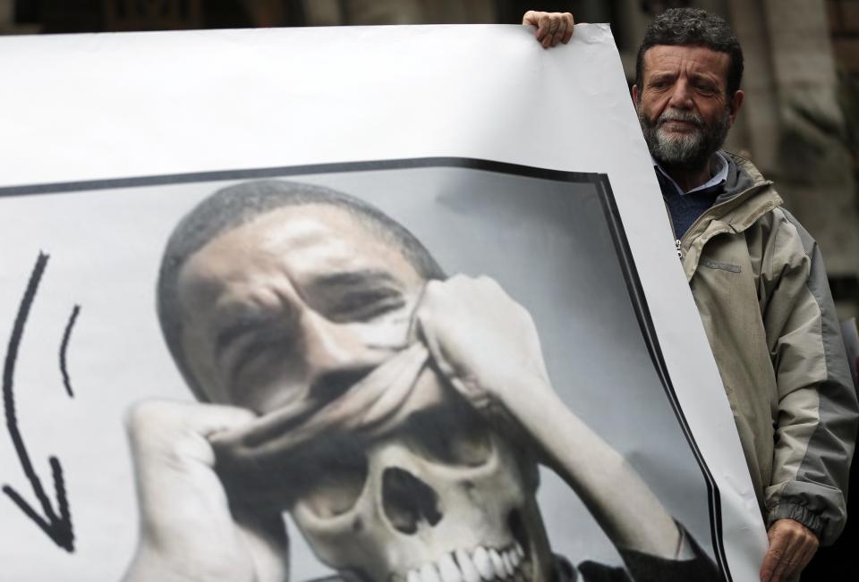 A demonstrator holds a banner during a protest against U.S. President Barack Obama near the U.S. Embassy in Rome, March 27, 2014. U.S. President Obama urged NATO allies on Thursday to get their defense budgets on an upward trajectory with "everybody pitching in" as he wounded up a day of meetings with Vatican and Italian officials. REUTERS/Yara Nardi (ITALY - Tags: POLITICS CIVIL UNREST)