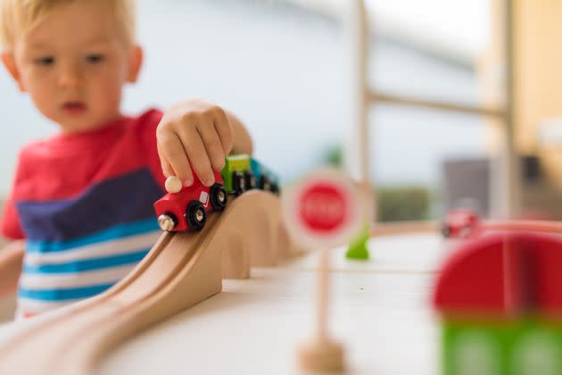 Little boy playing with wooden toy train.