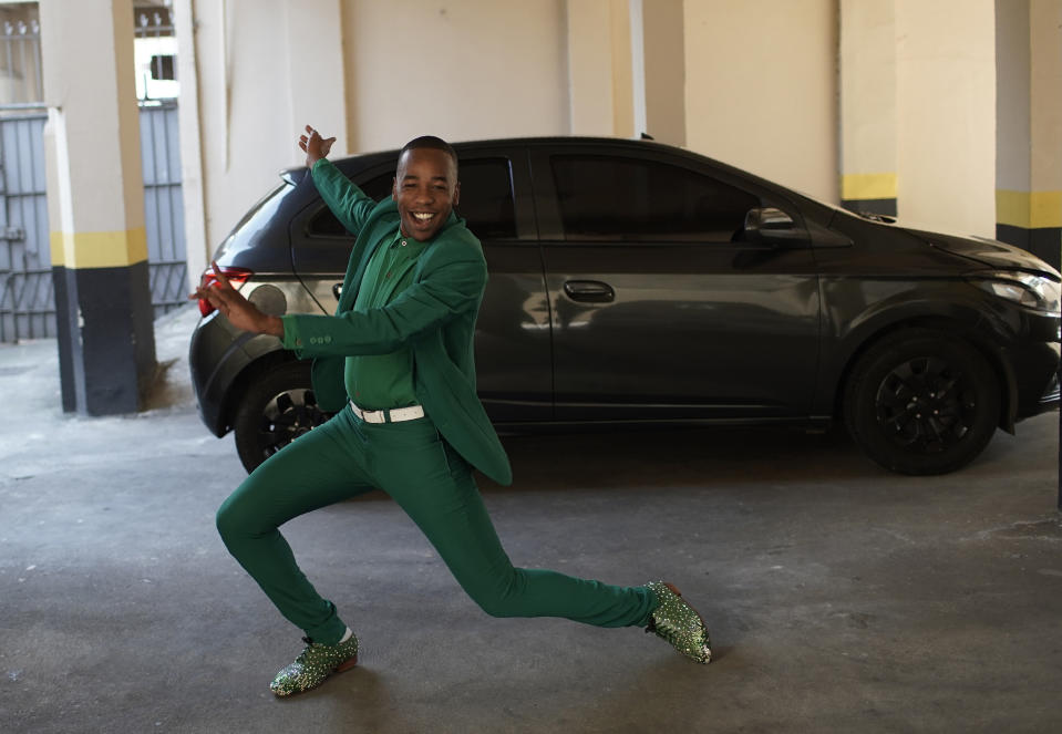 Diogo Jesus, the main dancer for the Mocidade Independente de Padre Miguel samba school, strikes a pose for reporters next to his car, in Rio de Janeiro, Brazil, Thursday, Sept. 17, 2020. Jesus, who is referred to as “master of ceremonies” in the school, could no longer make rent without his income from dancing at private events. Rio de Janeiro on Thursday, Sept. 24, said it has delayed its annual Carnival parade, saying the global spectacle cannot go ahead in February because of Brazil’s continued vulnerability to the new coronavirus pandemic. (AP Photo/Silvia Izquierdo)