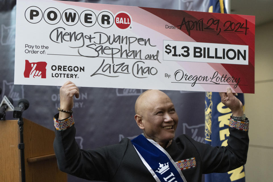 Cheng "Charlie" Saephan holds display check above his head after speaking during a news conference where it was revealed that he was one of the winners of the $1.3 billion Powerball jackpot at the Oregon Lottery headquarters on Monday, April 29, 2024, in Salem, Ore. (AP Photo/Jenny Kane)