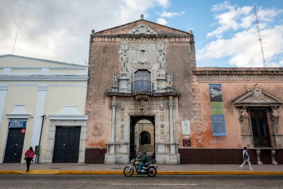 A motorcyclist passes by the Casa de Montejo, which dates from 1540 and is located on the south side of Plaza Grande in Merida, Mexico. It originally housed soldiers, but was soon converted into a mansion that served members of the Montejo family until the 1800s. Today it houses a bank and museum.