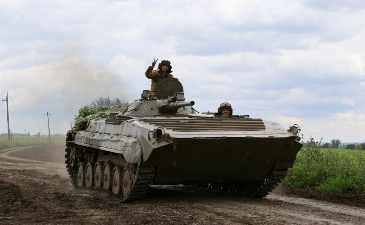 A Ukrainian serviceman from the 3rd Separate Assault Brigade flashes the V-sign as they ride an armoured personnel carrier (APC) at a road near the frontline city of Bakhmut (EPA)