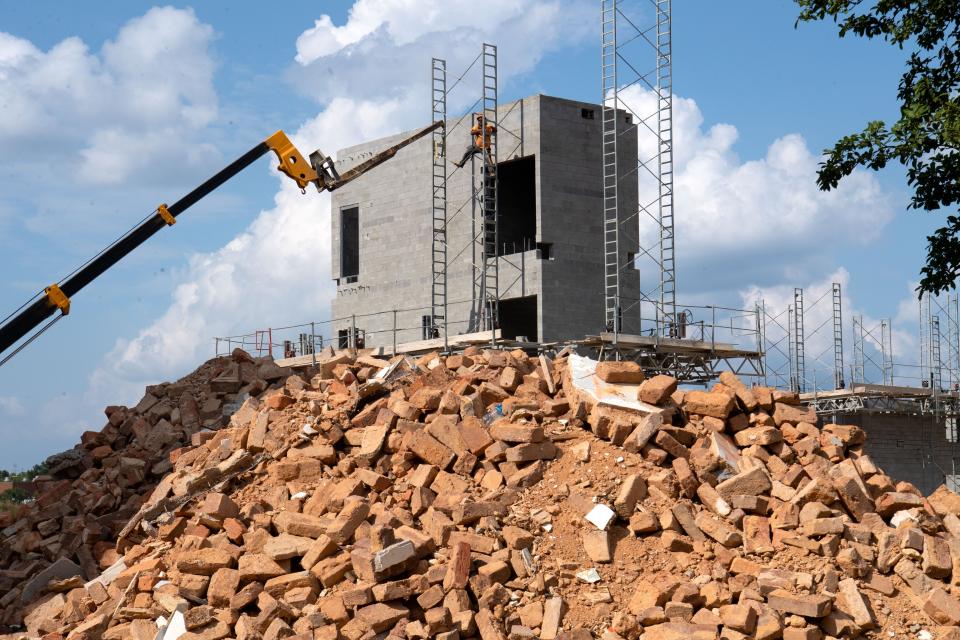 June 27, 2022; Tuscaloosa, AL, USA; A construction worker, with the aid of a crane, removes scaffolding from around a newly constructed elevator shaft on the new east wing at Bryce Main after the original wing had to be demolished. A pile of bricks that had been used in the original building lies in the foreground. Some of the bricks will be used in the reconstructed wing where feasible. Gary Cosby Jr.-The Tuscaloosa News