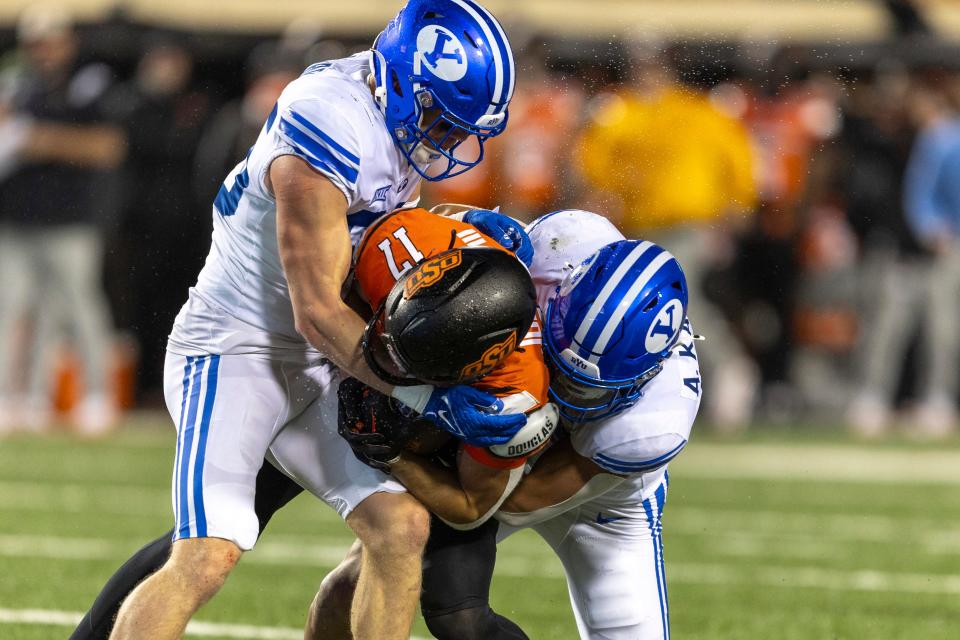 BYU safety Talan Alfrey, left, and linebacker Ace Kaufusi tackle Oklahoma State wide receiver Leon Johnson III (17).