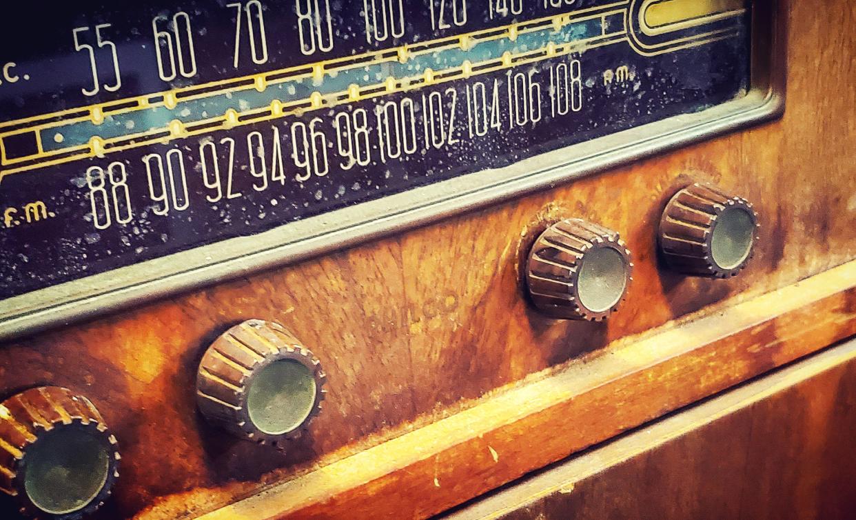 A closeup of an old radio made of wood with the tuner and dials.