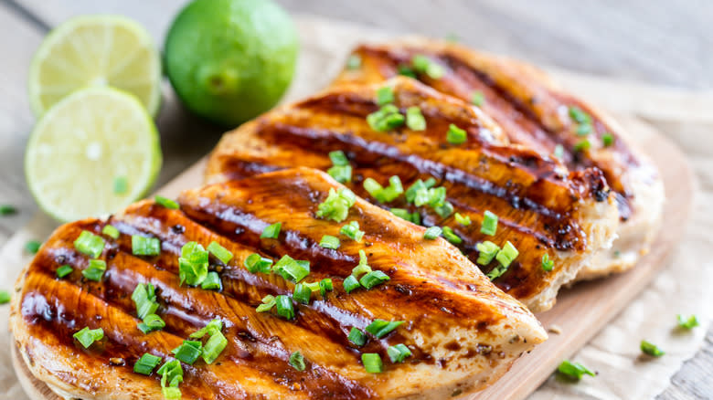 Grilled chicken breasts with limes in the background 