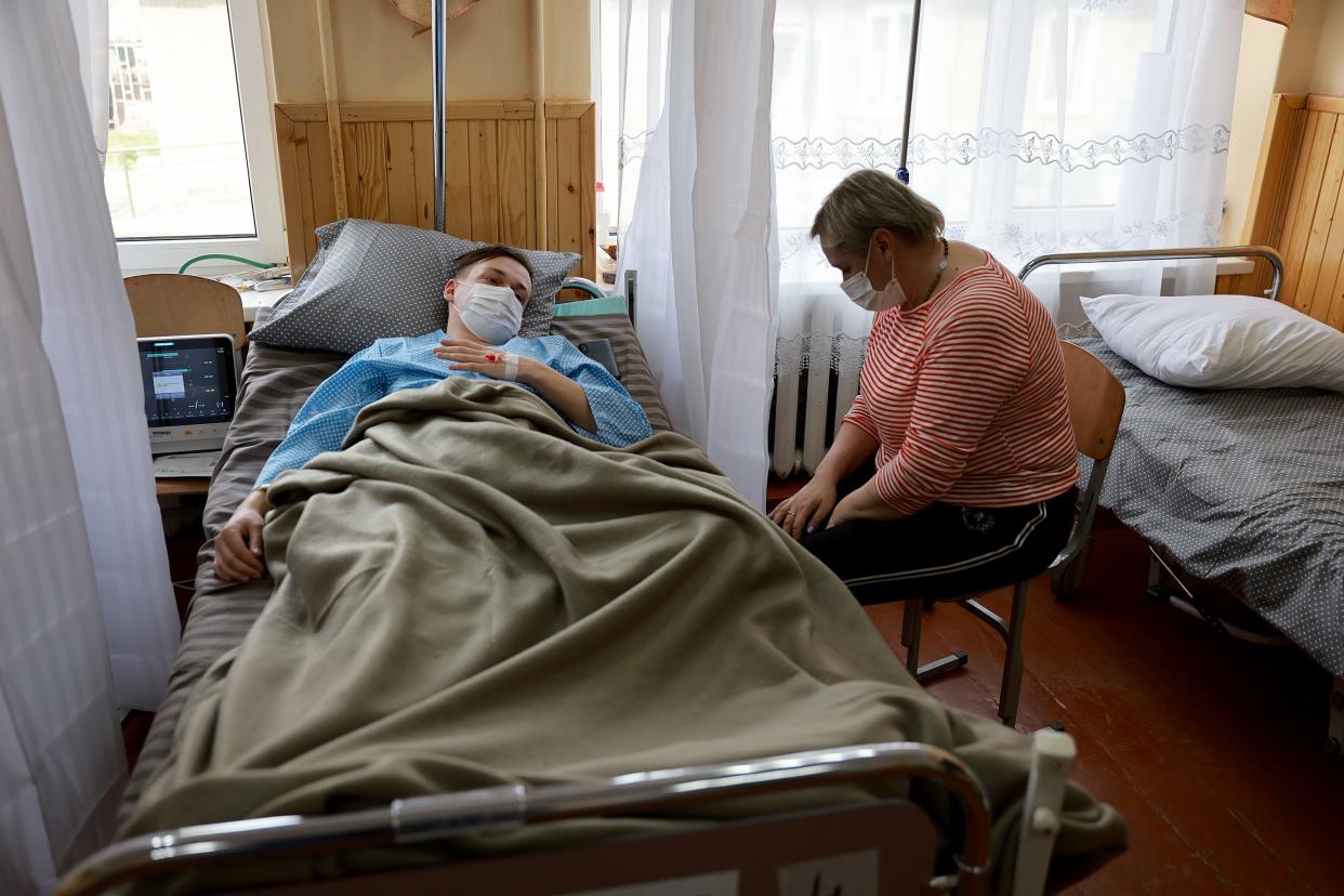 Nadia Stasishin sits with her son, Yura Stasishin, as he rests after being treated in an Israeli field hospital for an epileptic seizure on March 30, 2022, in Mostyska, Ukraine.
