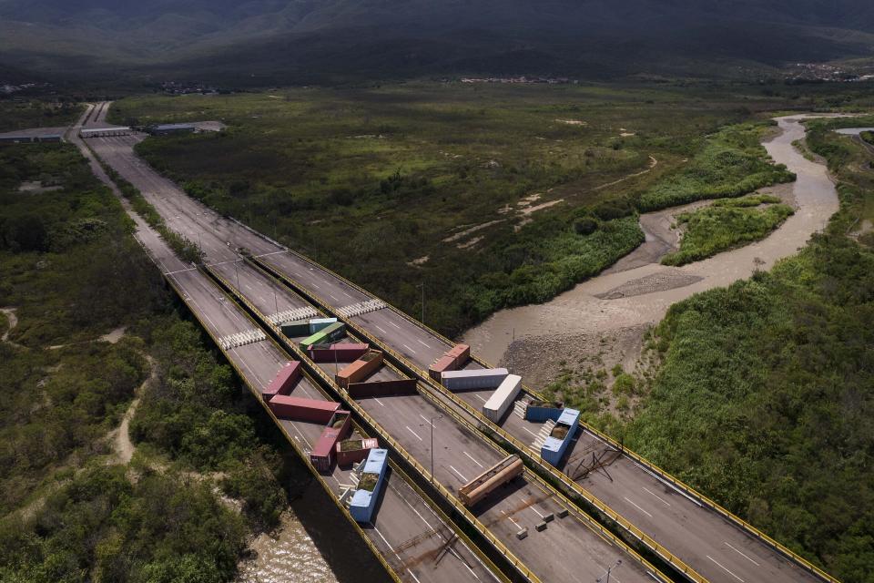 Containers block the Tienditas International Bridge, seen from Cucuta, Colombia, below, which connects with Tienditas, Venezuela, top, as the border has been partially closed for years by the Venezuelan government, Friday, Aug. 5, 2022. The border will gradually reopen after the two nations restore diplomatic ties when Colombia’s new president is sworn-in on Aug. 7, according to announcement in late July by Colombia’s incoming Foreign Minister Alvaro Leyva and Venezuelan Foreign Minister Carlos Faria. (AP Photo/Matias Delacroix)