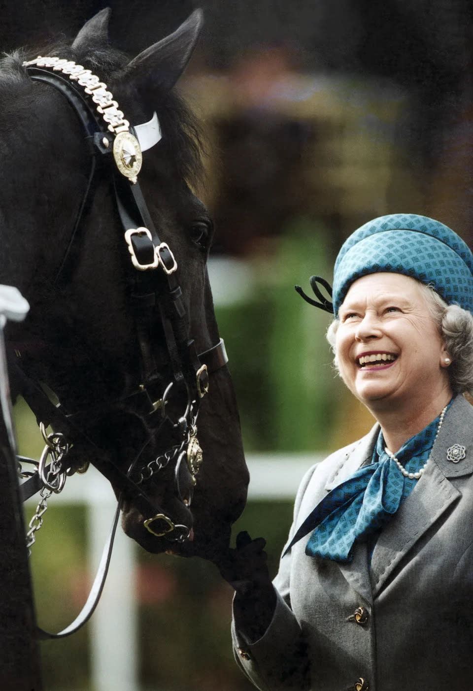 Königin Elizabeth II. lächelt, als sie bei der Royal Windsor Horse Show 1997 die auf Pferden reitenden Truppen beobachtet. (Getty Images)
