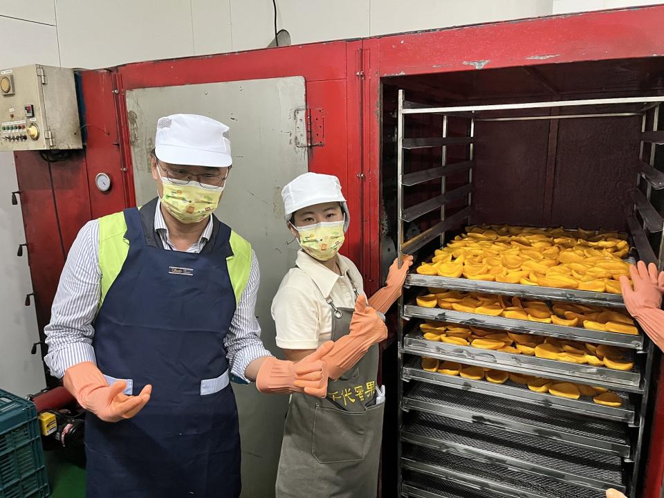 農委會主委陳吉仲（左）將削切好的芒果肉送進乾燥箱。（攝影／游昇俯）
